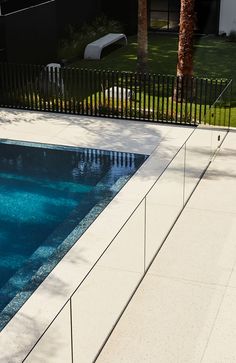 an empty swimming pool in the middle of a yard with palm trees and lawn furniture