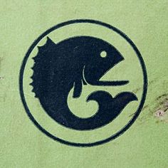 a fish logo is shown on the side of a green wall with peeling paint and rust