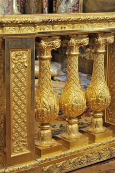 an ornate gold and black table with three vases on it's sides in front of a mirror