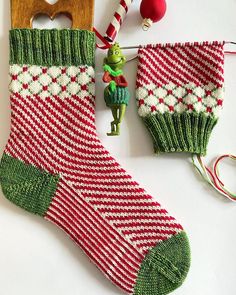 a knitted christmas stocking with a wooden ornament next to it on a white surface