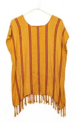 This light weight, soft blouse was hand-woven using 100% Cotton, Hilo Aleman. It is a versatile and vibrant piece that comes in a range of deep blue, red, and yellow shades. Each top features tassels that decorate and enriches each blouse. The striped pattern of this top is simple and subtle, yet the tassels add a flowy addition, which gives it motion and character. DETAILS Material: 100% Cotton, Hilo AlemaniaSize: 29.9" length x 18.5" - 76cm length x 47cm widthCare: Hand-wash in cold water, tre Casual Tunic Top With Tassels, Red Fringe Tops For Summer, Bohemian Cotton Blouse With Fringe, Casual Fringe Beach Blouse, Casual Fringe Blouse For The Beach, Casual Beach Blouse With Fringe, Beach Cotton Tops With Back Tassel Tie-up, Bohemian Striped Cotton Tops, Cotton Beach Tops With Tassels