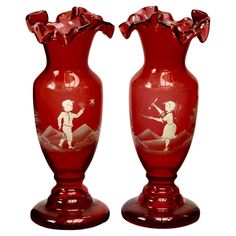 two red vases with designs on them sitting next to each other in front of a white background