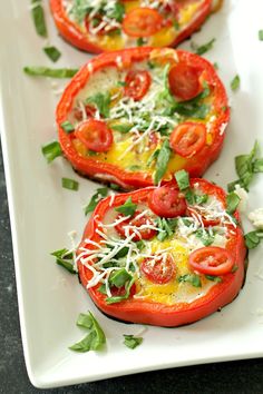 three tomatoes with cheese and herbs on them are sitting on a white plate, ready to be eaten