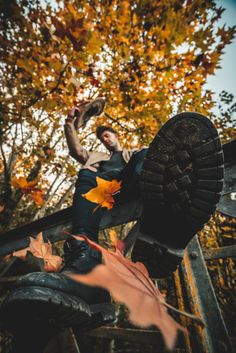 a man sitting on top of a metal bench in the fall with leaves around him