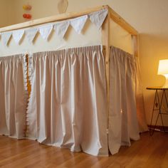 a baby crib with curtains on the top and bottom, next to a lamp