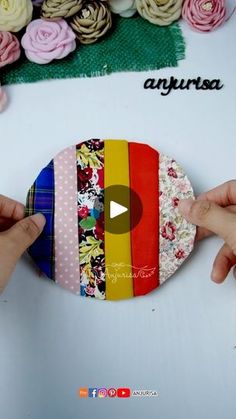 two hands are placing fabric on the top of a piece of paper with flowers in the background