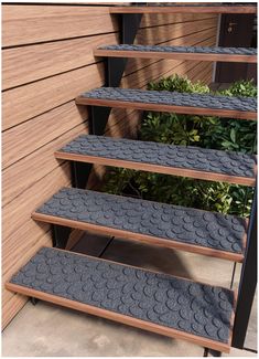 a set of four shelves sitting on top of a wooden floor next to green plants