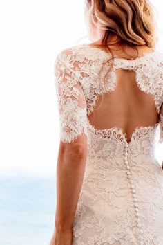 a woman in a wedding dress looking out at the ocean