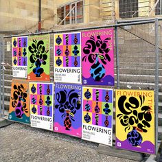 a bunch of colorful posters on the side of a building next to stairs and railings