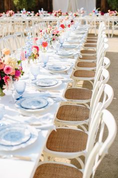 a long table with white chairs and blue plates