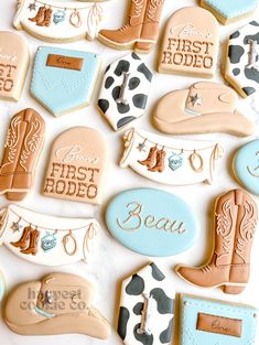 decorated cookies with cowboy boots and first rodeo designs are displayed on a white tablecloth