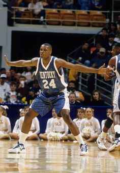 two basketball players in blue and white uniforms are on the court with their arms out