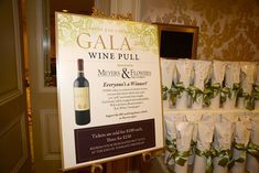 there is a sign that says gala wine pull with many bottles in front of it