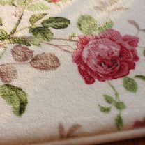 a close up of a flowered towel on a wooden table with white and red flowers