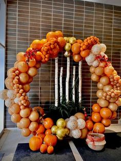 an orange and white wreath made out of balloons in front of a wall with candles