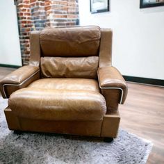 a brown leather recliner chair sitting on top of a white rug in front of a brick wall