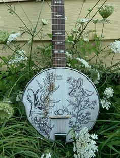 an old guitar sitting in the middle of some flowers