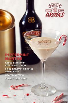 a martini with peppermint on the rim next to a bottle of booze and candy canes