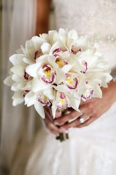 a bride holding a bouquet of white and red flowers