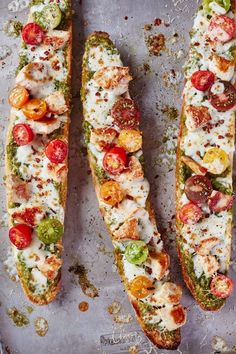 three pieces of bread with tomatoes, cheese and other toppings on them sitting on a baking sheet