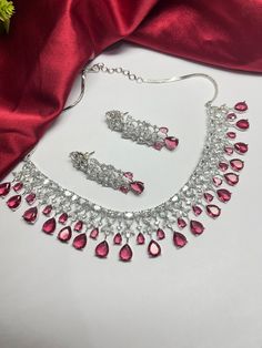 Gorgeous fine quality Wine Red dark pinkish zircon and  diamonds studded necklace with white gold rhodium plating and matching Earrings Item contains: Necklace and earrings AAA quality cubic zirconia used. Highest quality and craftsmanship Necklace Fitting is adjustable Earrings Closure: Pushback Necklace Closure: chain with adjustable length Hook Details-  -Handmade item -Delivery from a small business in India -Materials: white rhodium, stones, cz, zircon, American diamond -Jewellery type: Ear Necklace Closure, American Diamond Jewellery, Bridal Choker, Studded Necklace, Wear Necklaces, Jewelry Care Instructions, Red Necklace, Wedding Jewellery Necklace, American Diamond