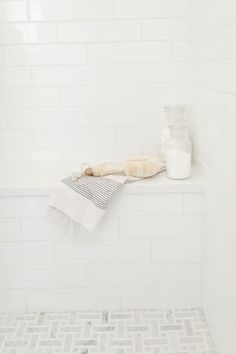 a white tiled bathroom with a bathtub and towel