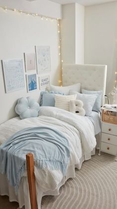 a bedroom with a bed, dresser and pictures on the wall above it is decorated in pastel blue and white