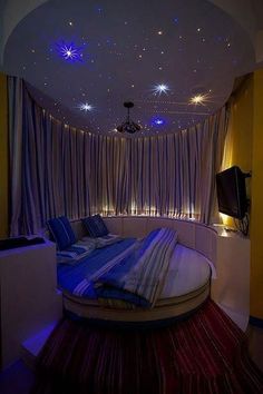 a round bed sitting in the middle of a room with lights on it's ceiling