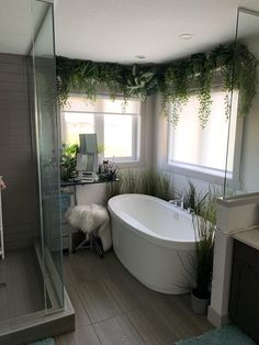 a bathroom with a tub, sink and plants in it