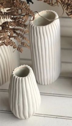 three white vases sitting next to each other on a window sill