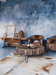 a living room with two chairs and a coffee table in front of a blue wall