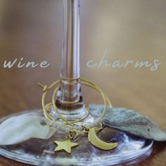 a wine glass sitting on top of a table next to a metal object with stars and moon charms hanging from it