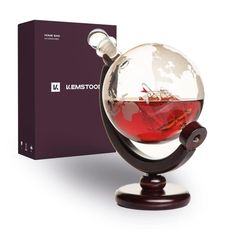 a glass globe with a red liquid in it sitting on a stand next to a box