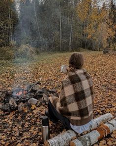 a person sitting on a log next to a campfire