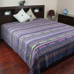 a bed with a colorful bedspread and two night stands on either side of it