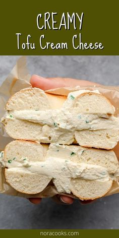 a hand holding a bagel with cream cheese on it and text overlay that reads creamy tofu cream cheese