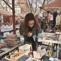 a woman standing over a table filled with books