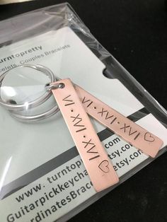 two metal key chains sitting on top of a package