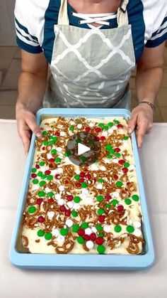 a woman in an apron is holding a pan with christmas cookies and sprinkles on it