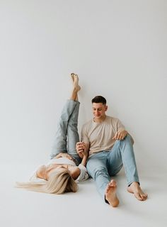 a man and woman laying on the ground with their feet up in the air while holding hands