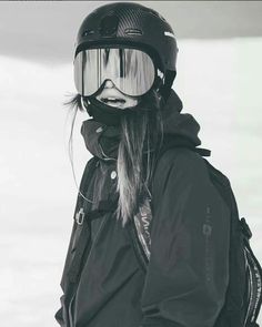 a woman wearing ski goggles and a helmet on top of her head is standing in the snow