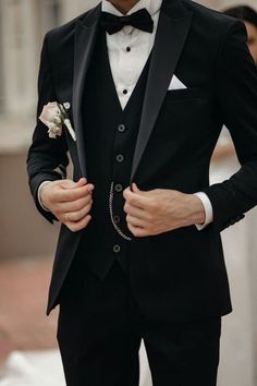 a man in a tuxedo is wearing a white rose boutonniere