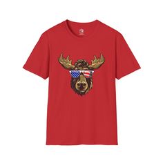 Experience the joy of American wildlife with The American Moose T-Shirt. This isn't just a shirt, it's an ode to the endearing charm and whimsical nature of our country's great wilderness.Prominently displayed on this shirt is a playful cartoon moose, its broad antlers and friendly grin brimming with character. It's sporting a pair of sunglasses, the lenses capturing the unmistakable stars and stripes of the American flag. Each detail, each stroke, pays tribute to the enchanting whimsy of our wi Red Short Sleeve T-shirt For Outdoor, Casual Red T-shirt For Outdoor Activities, Red Short Sleeve T-shirt For Outdoors, Red Tops With Graphic Print For Outdoor, Red Graphic Print Top For Outdoor, Cartoon Moose, American Wildlife, Whimsical Nature, Stars And Stripes