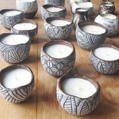 a table topped with lots of white candles sitting on top of a wooden table next to vases