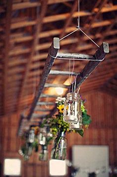 an old ladder is hanging from the ceiling with mason jars and sunflowers in it