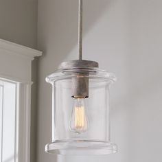 a light fixture hanging from a ceiling in a room with white walls and window frames