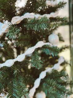 a close up of a christmas tree with white balls on it and snow flakes hanging from the branches