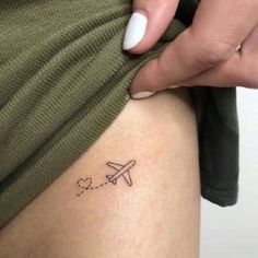 a woman with a small airplane tattoo on her thigh