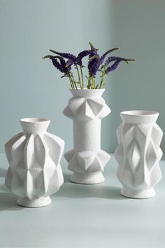 three white vases with purple flowers in them