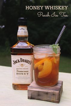 a bottle of jack daniels peach tea next to a wooden block with a glass full of it